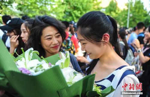 資料圖：山東濟(jì)南眾多考生手捧鮮花在家長(zhǎng)的簇?fù)硐職g快告別高考。中新社記者 張勇 攝