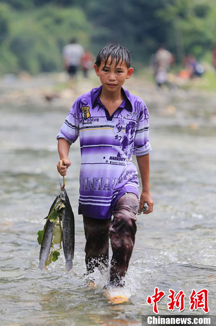圖為7月9日，一名男孩在鬧魚節(jié)活動中抓到了兩條魚。譚凱興 攝