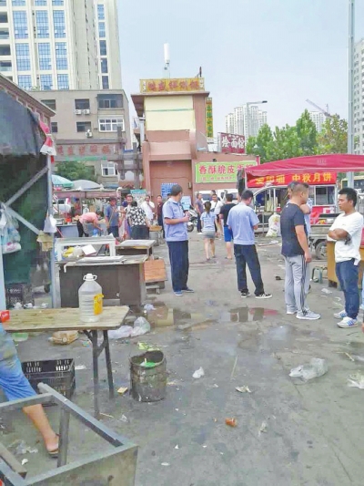 昨天，執(zhí)法人員在京廣路長江路口整治“僵尸圍擋”及圍擋內(nèi)的攤販。