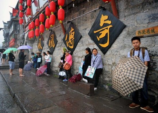 　4月29日上午11時20分，一些游客和古城當(dāng)?shù)氐木用穸阍谝粋€酒吧的屋檐下避雨。這些當(dāng)?shù)鼐用褚詾橛慰团恼罩\生，一場降雨讓他們的生意更加清淡。