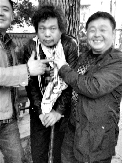 兩名接訪人員與患有癌癥的訪民段新德合影時，面帶笑容擺出勝利的手勢。