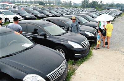 昨日，市民在山東棗莊一家拍賣公司場地上查看待拍賣公車。當(dāng)日，棗莊市103輛公車公開拍賣。新華社記者