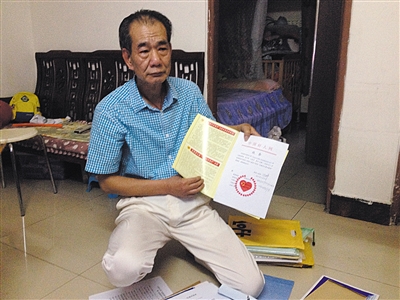 翻出一家網(wǎng)站贈予的“中國好人”證書，區(qū)少坤單膝跪在地上，“你看，我是中國好人啊?！?范春旭 攝