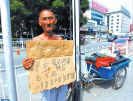 老人舉著牌子在路邊等候失主。京華時報記者譚青攝