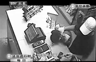 戴帽男子一手掐住加油站營業(yè)員，一手持發(fā)令槍指向另一營業(yè)員，要求“把錢給我裝起來”。