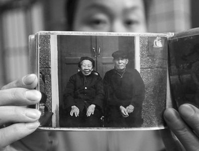 圖為孫女拿出兩位老人上世紀(jì)80年代在家門口的合影給記者看。記者楊濤 攝