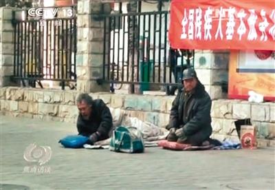 工人體育場北路，兩位乞討者路邊乞討，并輪流扮成“病人”（躺地者）。 央視截圖