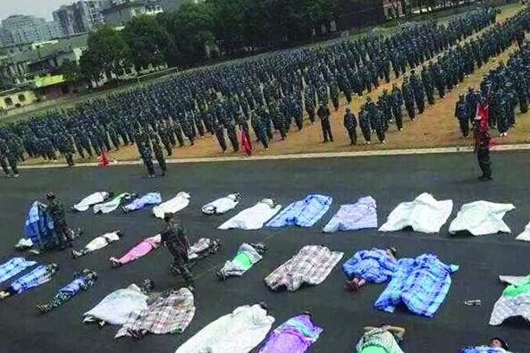 20多名女生躺在瀝青跑道上，身上嚴(yán)嚴(yán)實(shí)實(shí)地裹著棉被，接受太陽的照曬。