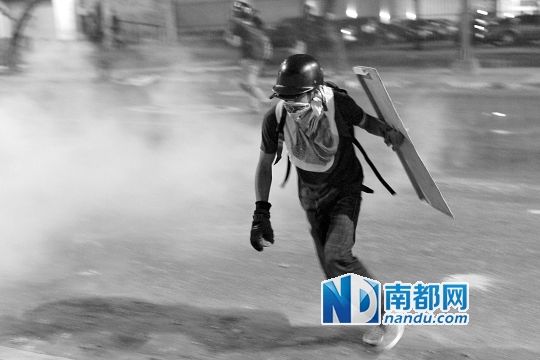 反政府示威者在與警察的沖突中躲避催淚彈。