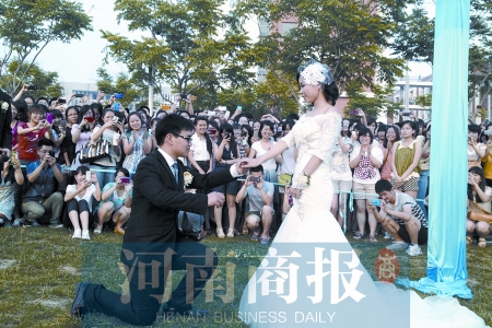 在學(xué)校操場的草坪上，兩名畢業(yè)生舉行婚禮，有同學(xué)感動地抹起眼淚