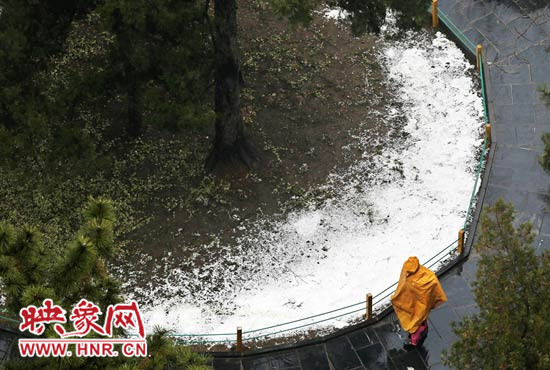 一位穿著雨衣的市民在雪中步行