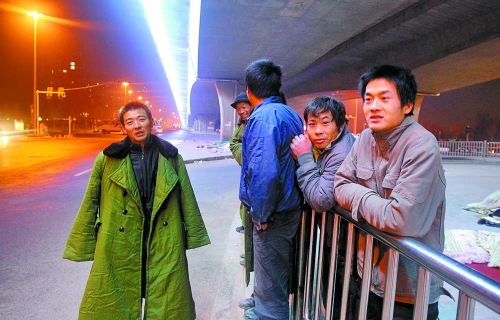 冬夜里，農(nóng)民工在橋下等著干活兒。