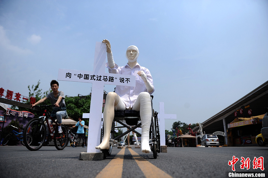 4月16日，重慶市洋人街上擺放著兩個(gè)受了傷的塑料人像“模特”，旁邊十字架上寫著向“中國(guó)式過(guò)馬路”說(shuō)不