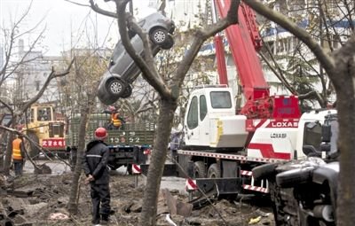 輸油管道爆炸后，搶修人員將被炸毀的車輛運(yùn)出現(xiàn)場。