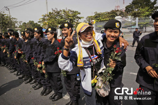 2013年12月03日,曼谷總理府與曼谷警署允許反政府示威民眾進入,雙方進入暫時“停戰(zhàn)”狀態(tài)迎接泰王生日。曼谷警察總署,女警們手持鮮花送給反政府示威民眾。圖片來源:Manish Swarup/東方IC
