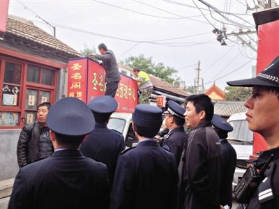 昨日下午,東城區(qū)工商、城管、公安等部門,對(duì)雍和宮附近的預(yù)測(cè)中心進(jìn)行清理整頓,站在車頂?shù)膬擅と苏鸪患摇邦A(yù)測(cè)中心”的招牌。因雍和宮、白云觀等文化景點(diǎn)外聚集大量算命先生,被媒體稱為“算命一條街”。本版攝影/新京報(bào)記者 李寧 攝