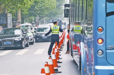 省人民醫(yī)院南門的路中間擺放反光錐，交警示意由西向東車輛從前方繞行。