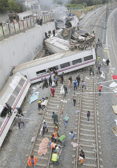 24日，救援人員在西班牙列車脫軌現(xiàn)場。一節(jié)車廂被強(qiáng)大的慣性拋上鐵道邊的高臺。