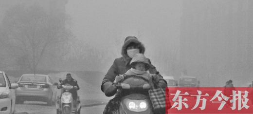 12月8日，鄭州市未來(lái)路上，一位市民帶著孩子在霧中騎行