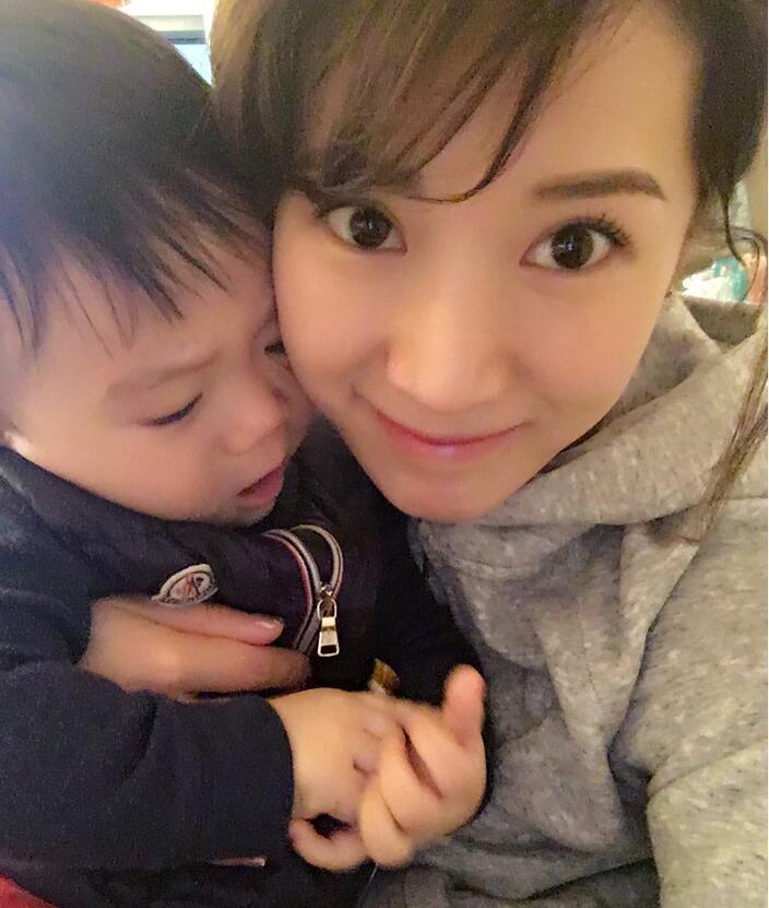 照片中李念狂吻兒子，小寶貝自顧自地玩著。
