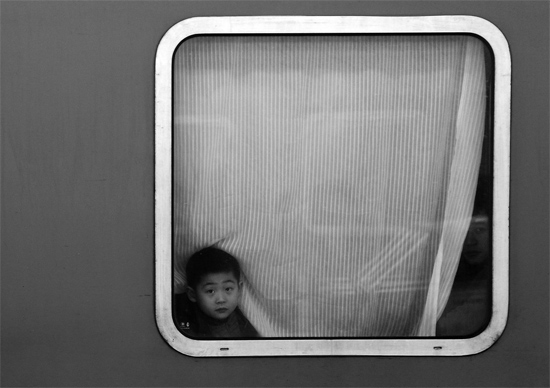 一個(gè)孩子把頭伸向窗外，他想再看送別的親人一眼
