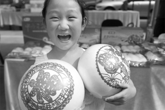 在2013河南食品安全宣傳周活動現(xiàn)場，一個小女孩抱著參展的特色大饅頭樂開了花