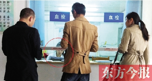 昨日，鄭州市二七區(qū)疾控中心辦證大廳，血檢窗口內(nèi)一名女工作人員，邊接受辦證者咨詢邊看報紙