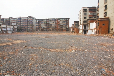 為降塵，旮旯王村拆遷后裸露的地面上鋪了一層石子。