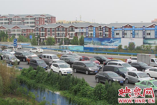 記者看到鄭州機(jī)場(chǎng)收費(fèi)站口車輛排隊(duì)，與此形成鮮明對(duì)比的是，路的對(duì)面（另一半幅）卻車輛較少，通行順暢。