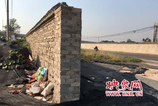 一墻之隔，一邊是道路，一邊是垃圾和荒草，市民質(zhì)疑其為遮羞墻。