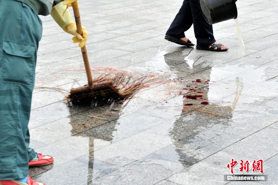 圖為環(huán)衛(wèi)工人在清理案發(fā)地點(diǎn)的血跡。