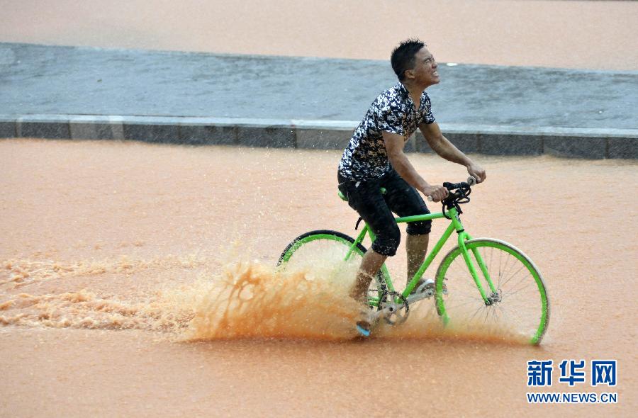 5月11日，一名行人在深圳街頭冒雨騎行。
