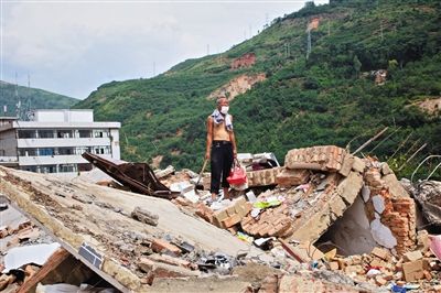 8月9日,龍頭山鎮(zhèn),一位老者在自家房屋廢墟上尋找家當(dāng)。