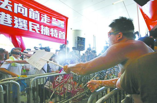 17日，在香港立法會外，一名反對政改的男子向支持派人群投擲標牌。