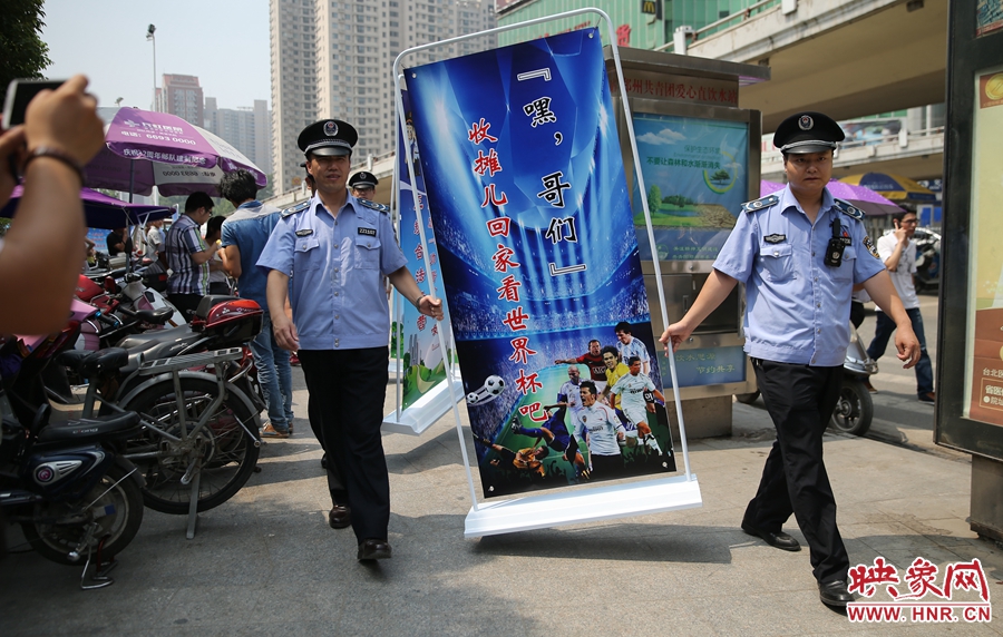 7月2日上午，鄭州市紫荊山地鐵站出入口，執(zhí)法人員抬著寫有勸導(dǎo)語的宣傳板，前往占道經(jīng)營攤位“圍觀執(zhí)法”