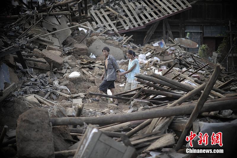 2014年8月5日，云南昭通龍頭山鎮(zhèn)老街，一對(duì)夫妻從居住房屋的廢墟中走過。