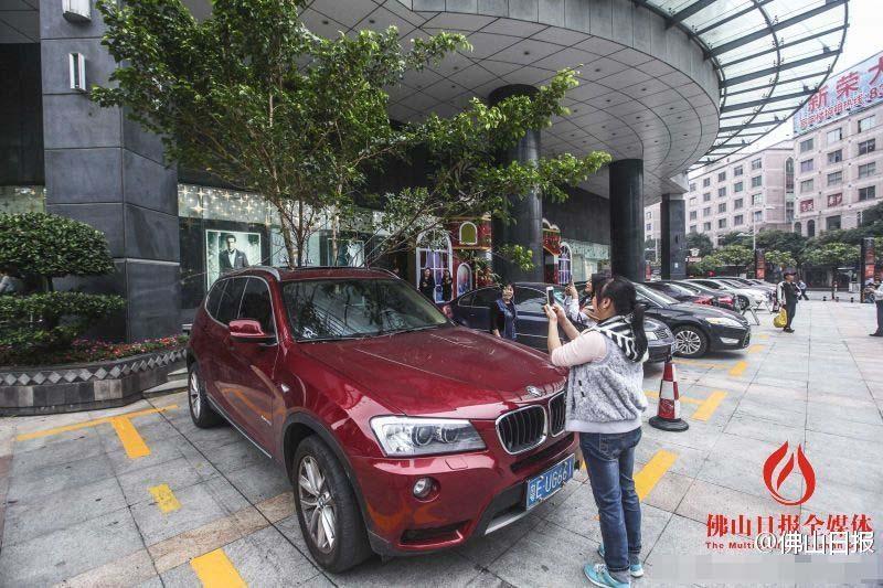 一輛停在停車位上的寶馬轎車，被墜落的樹枝砸中，樹枝徑直插入車內(nèi)，現(xiàn)場(chǎng)引發(fā)不少市民圍觀拍照。