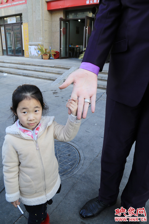 巨人“張歡”牽著一名漂亮的小女孩，兩人的手大小對(duì)比非常明顯。
