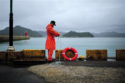 7月6日，韓國珍島，一名海岸警察在港口系救生圈。4月，客輪在珍島近海發(fā)生沉船事故后，仍有11人下落不明。