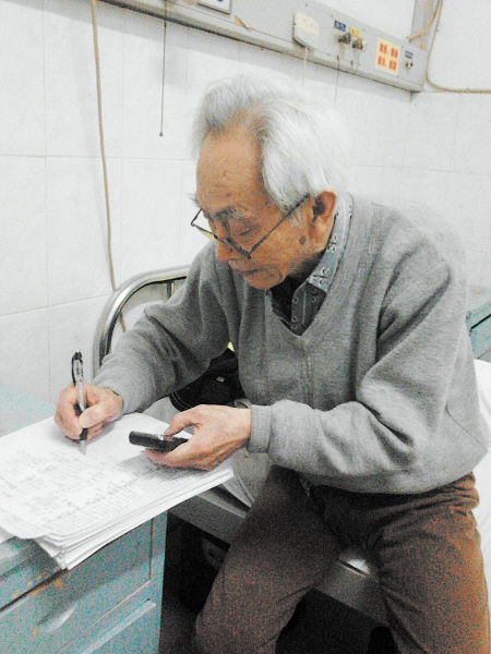 杜修源老人埋頭寫著特殊的“日記”。 李卓 攝