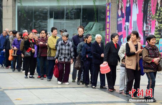 圖為10月28日，在江西九江市一家羊絨皮草服裝服飾博覽會現(xiàn)場，老人們正在頂著寒風排隊等待領取10元代金劵。