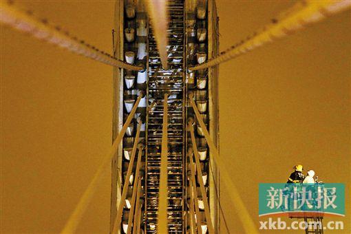 截至今日零時(shí)，男子仍未有下橋舉動(dòng)。圖為公安和消防人員乘消防云梯在高空上和男子交談。